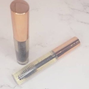 May include: Two gold and clear tubes of eyelash serum. The tubes have a brush applicator and a gold cap.