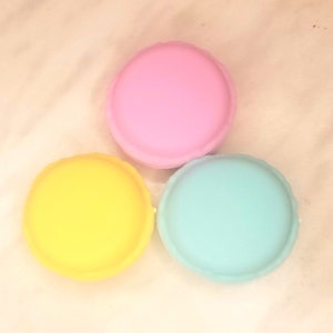 Puede incluir: Tres macarons redondos y coloridos. Uno es rosa, otro amarillo y otro azul claro.