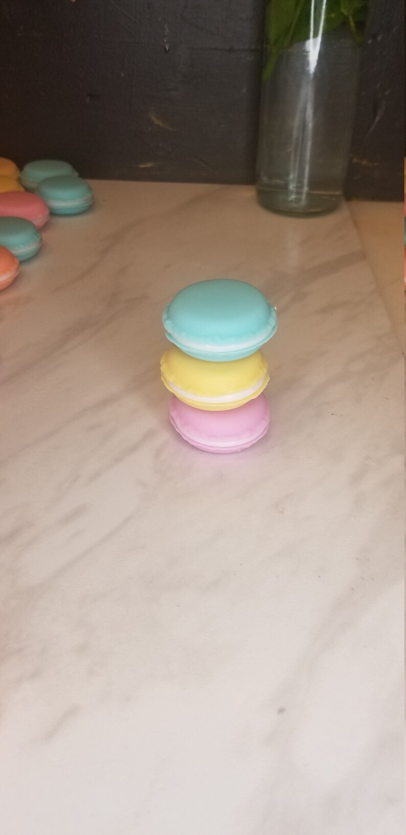 Puede incluir: Una pila de tres macarons de color pastel. El macaron de arriba es azul claro, el macaron del medio es amarillo y el macaron de abajo es rosa.