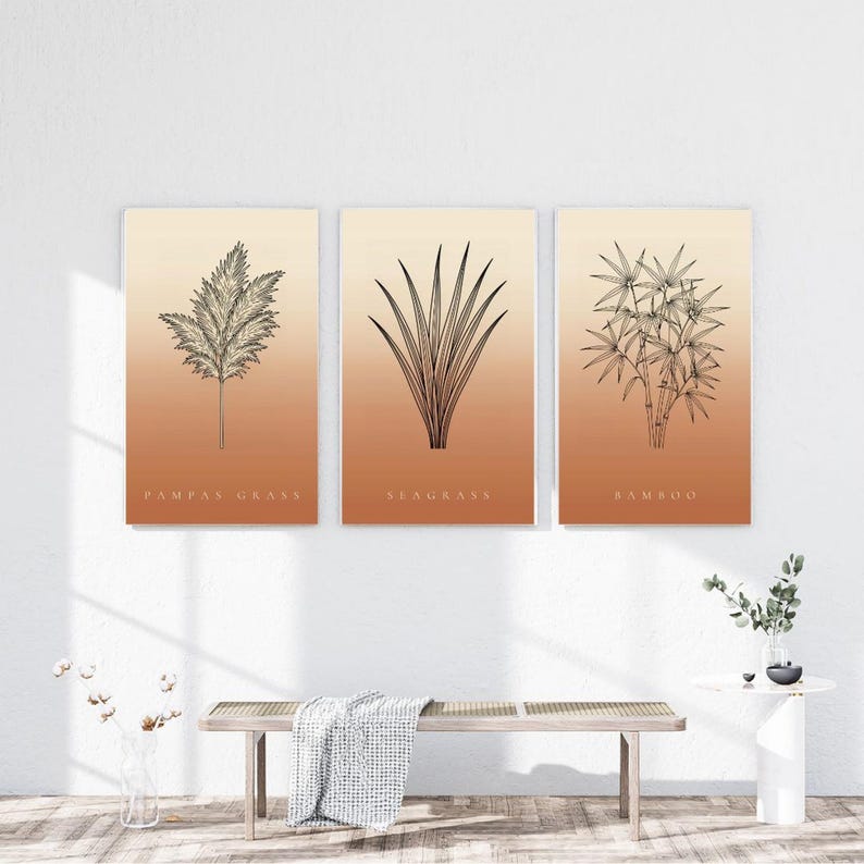 Peut inclure: Un ensemble de trois affiches murales rectangulaires pr&eacute;sentant des dessins au trait noir de pampas, d'herbes marines et de bambou. Chaque affiche a un fond d&eacute;grad&eacute; passant du cr&egrave;me clair en haut &agrave; un orange terre cuite chaud en bas.