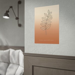May include: A rectangular wall poster featuring a black line art illustration of a eucalyptus branch centered on a vertical gradient background that transitions from light cream at the top to a warm terracotta orange at the bottom with the text EUCALYPTUS.