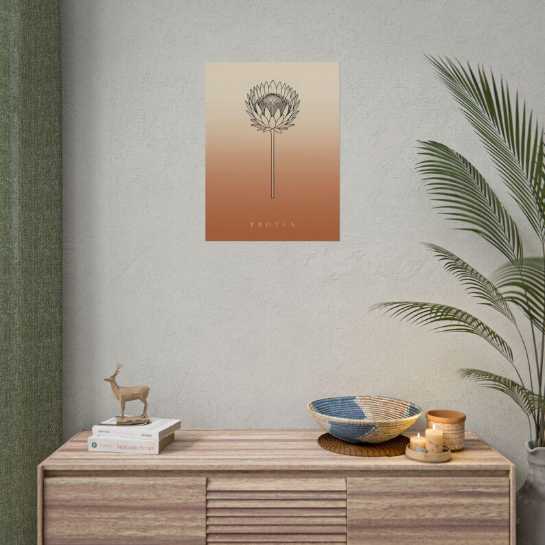 Pu&ograve; includere: Una stampa artistica da parete rettangolare con un disegno a linee nere di un fiore di protea centrato su uno sfondo a gradiente verticale che sfuma dal beige chiaro in alto all'arancione terracotta intenso in basso con il testo PROTEA.