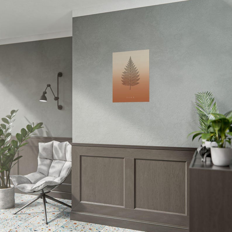 K&ouml;nnte beinhalten: Ein rechteckiger Wandkunstdruck mit einer dunkelbraunen Farnblatt-Illustration, die auf einem Farbverlauf zentriert ist, der von einem hellen Beige oben zu einem tiefen gebrannten Orange unten &uuml;bergeht, mit dem Wort FERN in kleinen Buchstaben.