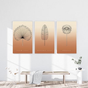May include: A set of three rectangular wall art prints featuring black line drawings of a palm leaf, a banana leaf, and a protea flower. Each print has a gradient background transitioning from light cream to a warm terracotta orange.