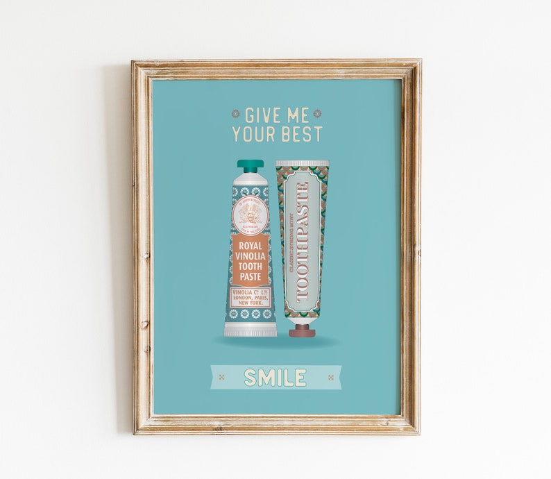 May include: A framed print with a blue background featuring two tubes of toothpaste. The text on the print reads "Give me your best" and "Smile".