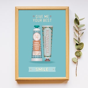 May include: A framed print with a light blue background featuring two vintage-style toothpaste tubes. The text on the print reads "Give me your best" and "Smile".