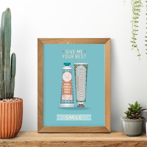 May include: A framed print with a blue background and the text "Give me your best smile" in white. Two tubes of toothpaste are shown, one with the text "Royal Vinolia Tooth Paste" and the other with the text "Classic Toothpaste".