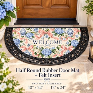 Puede incluir: Un felpudo de goma semicircular con un inserto de fieltro que presenta un patrón floral de hortensias azules, cintas rosas y jarrones azules y blancos. El texto WELCOME está impreso en el centro. Disponible en 25,4 cm x 55,9 cm y 30,5 cm x 61 cm.