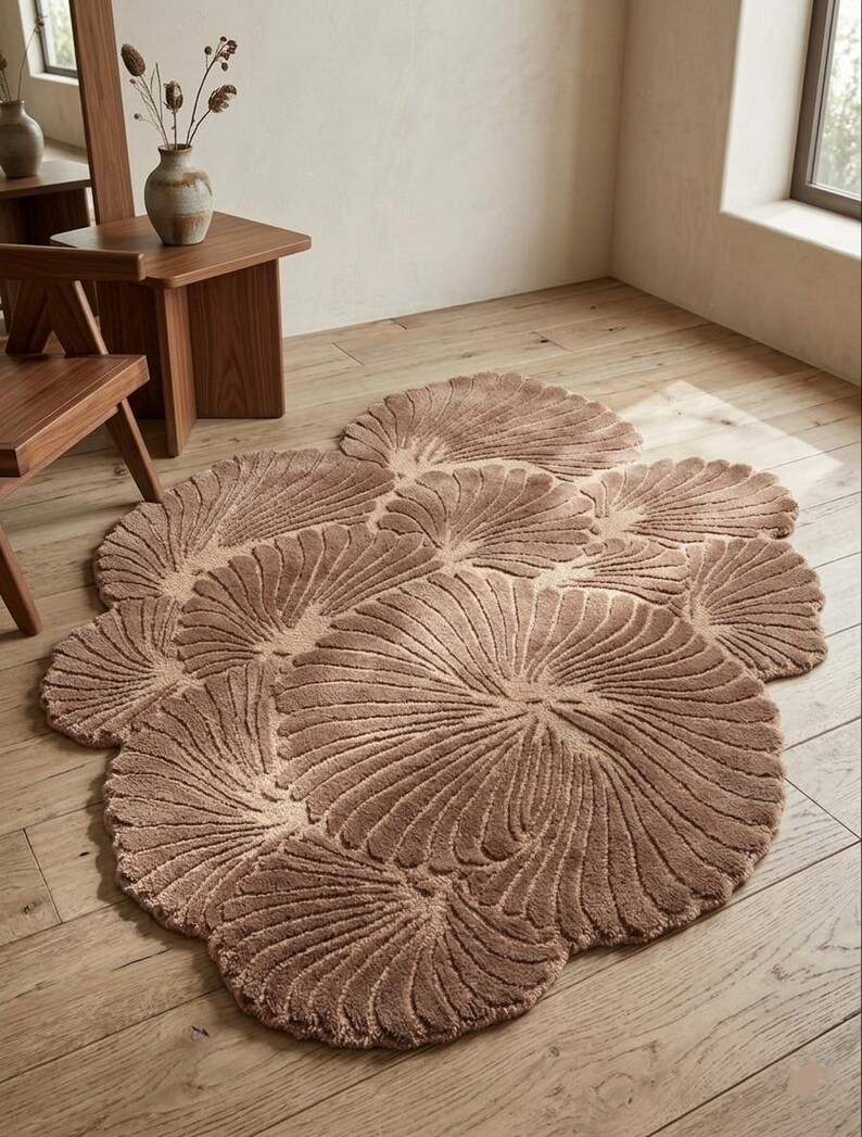 May include: A large, irregularly shaped area rug featuring a textured, tufted surface in a warm, earthy brown tone. The rug is composed of multiple overlapping circular and fan-like segments, each displaying a radiating, grooved pattern.