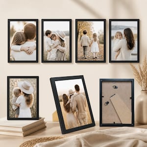 Może przedstawiać: Zestaw sześciu prostokątnych czarnych ramek na zdjęcia. Cztery ramki są zamontowane na ścianie, każda z fotografią osób na zewnątrz. Dwie dodatkowe ramki znajdują się na powierzchni, jedna pokazuje zdjęcie, a druga tylną stronę.