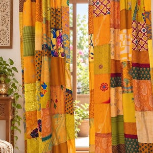 Pode incluir: Um par de cortinas de comprimento total com um design de patchwork vibrante composto por vários quadrados de tecido em tons de amarelo, laranja, verde e vermelho. Os painéis exibem uma mistura de padrões florais, paisley e geométricos.