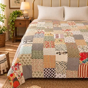 Puede incluir: Una colcha de patchwork que presenta una variedad de bloques de tela cuadrados con diversos patrones, incluyendo diseños florales, geométricos y de rayas en tonos apagados de rojo, verde, amarillo, azul y crema, sobre una cama con dos almohadas blancas.