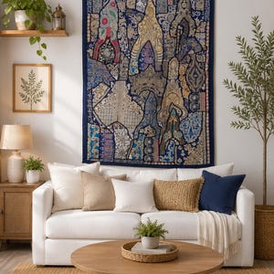 Könnte beinhalten: Ein rechteckiger Wandbehang mit einem dunkelblauen Rand und einem komplexen Patchwork-Design aus verschiedenen komplizierten Mustern in Gold-, Blau- und Cremetönen. Das Textil zeigt mehrere bogenförmige Formen und detaillierte Stickereien.
