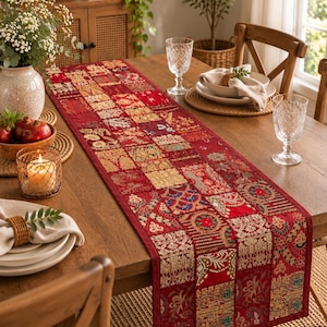 K&ouml;nnte beinhalten: Ein langer, rechteckiger Tischl&auml;ufer mit einem Patchwork-Design aus verschiedenen roten Stoffquadraten. Jedes Quadrat ist mit aufwendigen goldenen, gr&uuml;nen und blauen Stickereien, Blumenmustern und metallischen F&auml;den im gesamten Textil verziert.