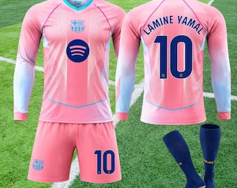 May include: A pink and light blue long-sleeve soccer jersey with the FC Barcelona crest, Spotify logo, and number 10. The back displays LAMINE YAMAL and number 10. Includes matching pink shorts with number 10 and blue soccer socks.