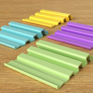 May include: Four plastic strips with a corrugated design in different colors: light blue, yellow, green, and purple. The strips are arranged in a staggered pattern on a wooden surface.