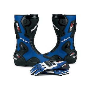 Puede incluir: Un par de botas de moto azules y negras con el logotipo de Suzuki y la marca MR, acompañadas de un par de guantes de moto a juego en azul, blanco y negro con acolchado protector y el logotipo de Suzuki impreso en la zona de la muñeca.