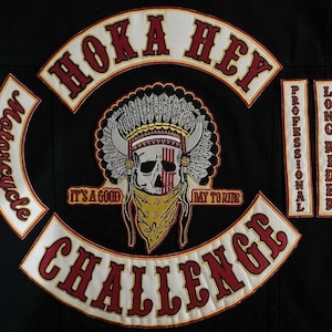 Könnte beinhalten: Eine schwarze Stoffweste mit gestickten Aufnähern. Der mittlere Aufnäher zeigt einen Totenkopf mit Federschmuck und einem gemusterten Halstuch. Der Text lautet HOKA HEY, CHALLENGE, IT'S A GOOD DAY TO RIDE, MOTORCYCLE, PROFESSIONAL und LONG RIDER.