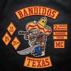 Peut inclure: Une veste en cuir noir avec des écussons brodés, dont une grande figure centrale représentant un personnage de dessin animé portant un sombrero et tenant un pistolet et une machette, avec le texte BANDIDOS, TEXAS, 13 MOTOR CYCLE, 1%, 1%ER, 2ND BANDIDO et MC.