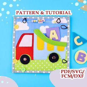 Puede incluir: Una página de libro de tela con un camión rojo y azul claro con una caja verde, una letra A amarilla y un fondo de cielo azul. La página incluye botones amarillos, bucles elásticos negros y una cuenta de helicóptero. Texto PATTERN & TUTORIAL.