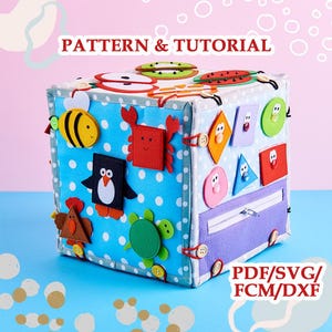 May include: A fabric activity cube featuring the text PATTERN & TUTORIAL and PDF/SVG/FCM/DXF. The cube has a blue polka dot base with felt appliques of a bee, crab, penguin, turtle, and various geometric shapes, plus a zipper and wooden buttons.