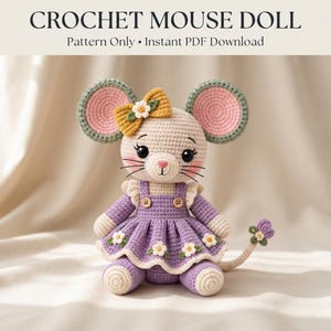 May include: A crochet mouse doll featuring a cream-colored head with pink inner ears, black eyes, and a yellow bow with a white flower. The mouse wears a purple dress with white flower appliqués, two small buttons, and a matching tail with a flower.