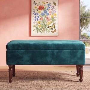 May include: A rectangular storage bench upholstered in deep teal velvet fabric. The bench features a smooth, flat top and a structured base supported by four dark brown, turned wooden legs. The design is simple, functional, and clean-lined.