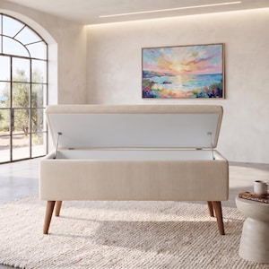 May include: A rectangular storage bench upholstered in cream-colored corduroy fabric with a vertical ribbed texture. The bench features a hinged lid that opens to reveal a white interior compartment, supported by four tapered wooden legs in a light brown finish.
