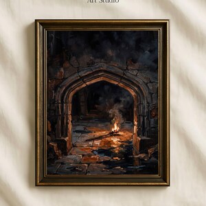 May include: A framed art print titled Vintage Paper Art Studio featuring an oil painting of a dark stone archway with a single burning torch on the ground, casting orange light and reflections across the uneven floor in a dim, cavernous space.