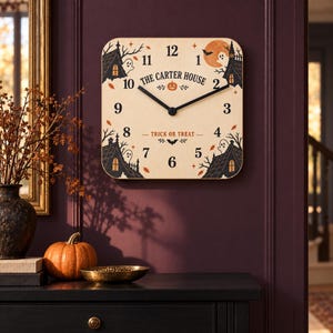 May include: A square wooden wall clock featuring a Halloween theme with black house silhouettes, ghosts, bats, and a full moon. The center displays the text THE CARTER HOUSE and TRICK OR TREAT with black clock hands and standard numerals 1 through 12.