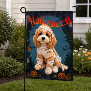 May include: A rectangular garden flag featuring a golden-brown puppy wrapped in white mummy bandages. The background displays a dark blue night scene with a haunted castle, spiderwebs, bats, ghosts, and orange jack-o'-lanterns. The word Halloween is printed in red at the top.