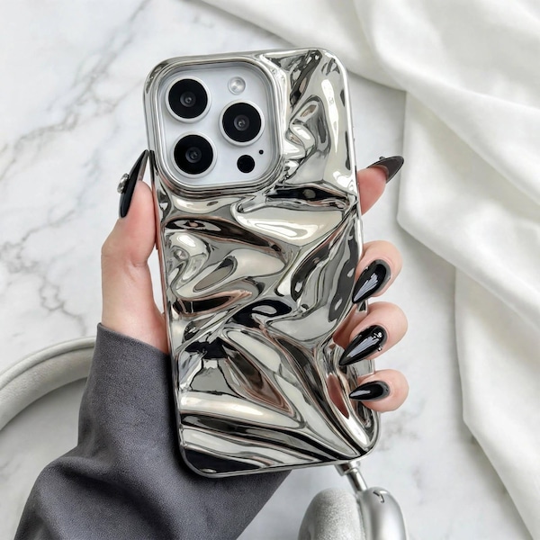 Könnte beinhalten: Eine silberfarbene Smartphone-Hülle mit einer stark reflektierenden Flüssigmetall-Optik. Die Oberfläche weist unregelmäßige, organische Falten und Vertiefungen auf, die ein verzerrtes, spiegelndes Finish erzeugen. Mit Aussparung für eine Dreifachkamera.
