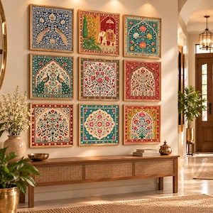 May include: A gallery wall arrangement of nine square framed prints featuring intricate floral, peacock, and elephant motifs in vibrant shades of blue, red, green, and gold, displayed in a grid pattern above a long wooden console table.