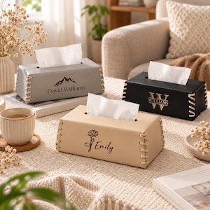Puede incluir: Tres cajas rectangulares para pañuelos en gris, negro y beige, con detalles de cordones en los laterales. La caja gris muestra un gráfico de montaña y el nombre David Williams. La negra tiene un monograma W. La beige presenta un gráfico de flor y el nombre Emily.
