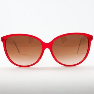 May include: Red cat-eye sunglasses with brown gradient lenses.