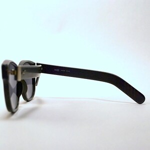 May include: Black sunglasses with a dark gray lens and a black frame. The frame has a slight curve to it and the arms are straight.