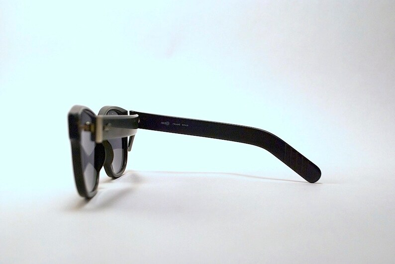 May include: Black sunglasses with a dark gray lens and a black frame. The frame has a slight curve to it and the arms are straight.