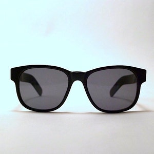 May include: Black sunglasses with a classic rectangular frame and dark lenses.