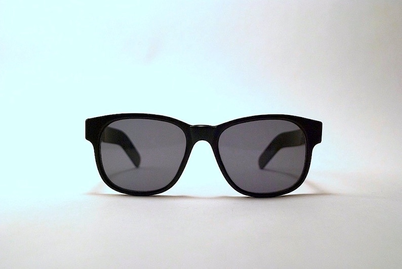 May include: Black sunglasses with a classic rectangular frame and dark lenses.