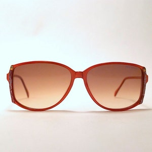 Könnte beinhalten: Eine rote Sonnenbrille aus Kunststoff mit braunen Verlaufsgläsern.