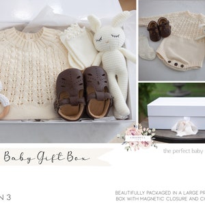 K&ouml;nnte beinhalten: Eine wei&szlig;e Geschenkbox gef&uuml;llt mit Babyartikeln, darunter ein gestrickter Pullover, ein Paar braune Schuhe, ein gestricktes H&auml;schen, eine Rassel und ein Paar Socken. Die Box ist mit einem wei&szlig;en Band verziert und der Text "Baby Gift Box" steht auf der Vorderseite.