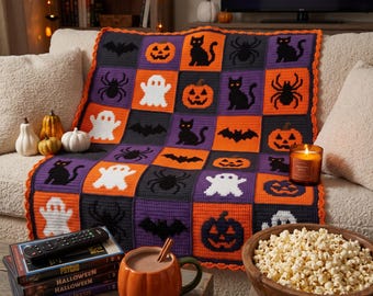 May include: A crochet blanket featuring a grid of squares with Halloween motifs including black cats, white ghosts, orange jack-o'-lanterns, black spiders, and black bats. The blanket has a scalloped orange border and is draped over a sofa.