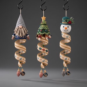 Puede incluir: Tres adornos colgantes con un gnomo de ganchillo, un árbol de Navidad de ganchillo y un muñeco de nieve de ganchillo. Cada figura está unida a una larga cinta beige en espiral con patrones botánicos bordados y pequeños dijes de ciervo.