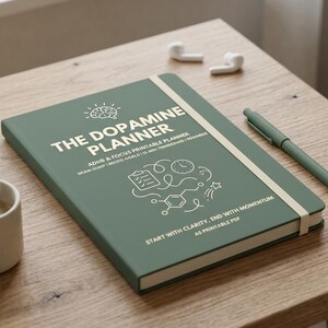May include: A sage green planner with a cream elastic band, featuring the white text THE DOPAMINE PLANNER, ADHD & FOCUS PRINTABLE PLANNER, BRAIN DUMP | MICRO-GOALS | 10-MIN TIMEBOXING | REWARDS, and START WITH CLARITY, END WITH MOMENTUM AS PRINTABLE PDF.