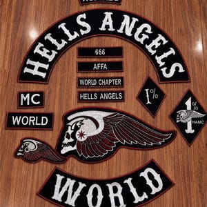 Könnte beinhalten: Eine Sammlung bestickter Aufnäher mit den Schriftzügen HELLS ANGELS, NOMADS, MC, WORLD, 666, AFFA und WORLD CHAPTER. Enthält zwei rautenförmige Aufnäher mit 1%-Symbolen und ein großes geflügeltes Totenkopf-Emblem mit roten und weißen Stickereien.