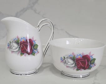 Juego de jarra de leche y azucarero de porcelana fina Queen Anne, con diseño floral de rosas inglesas y ribete plateado.