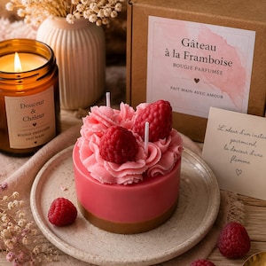 Peut inclure: Une bougie cylindrique en forme de gâteau rose, surmontée d'un glaçage en cire rose et de deux framboises en cire réalistes. La bougie repose sur une assiette en céramique mouchetée à côté d'une boîte en carton marquée Gâteau à la Framboise.