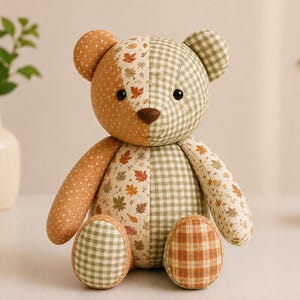 Puede incluir: Un oso de peluche hecho de paneles de tela de patchwork. El oso presenta un dise&ntilde;o dividido con un lado en patrones de puntos y cuadros naranjas, y el otro en cuadros vichy verdes. El panel central muestra un estampado de hojas de oto&ntilde;o.
