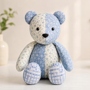 Puede incluir: Un oso de peluche hecho de tela de retazos con un dise&ntilde;o dividido. Un lado muestra un patr&oacute;n floral azul claro, mientras que el otro lado presenta un estampado floral azul m&aacute;s oscuro. Los pies est&aacute;n cubiertos con un patr&oacute;n de cuadros vichy azul.