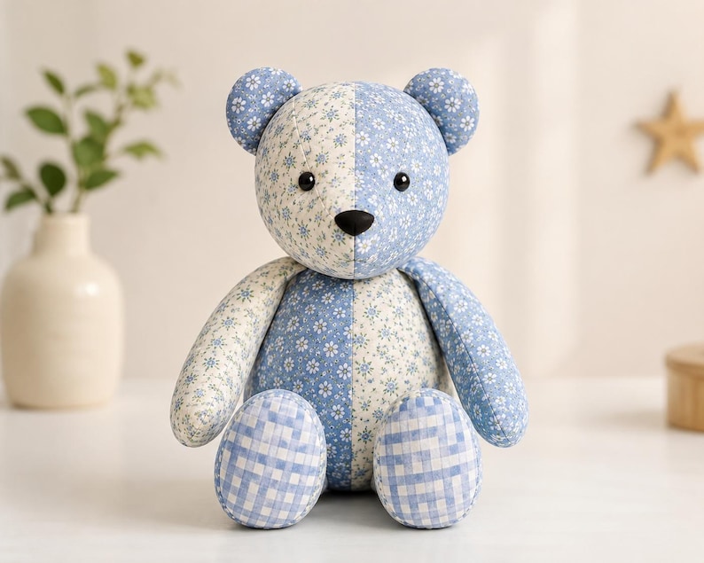 Puede incluir: Un oso de peluche hecho de tela de retazos con un dise&ntilde;o dividido. Un lado muestra un patr&oacute;n floral azul claro, mientras que el otro lado presenta un estampado floral azul m&aacute;s oscuro. Los pies est&aacute;n cubiertos con un patr&oacute;n de cuadros vichy azul.